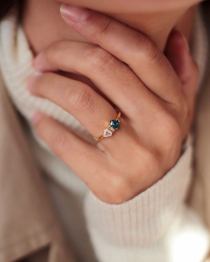 a close up of a person wearing a gold ring with an emerald stone on it