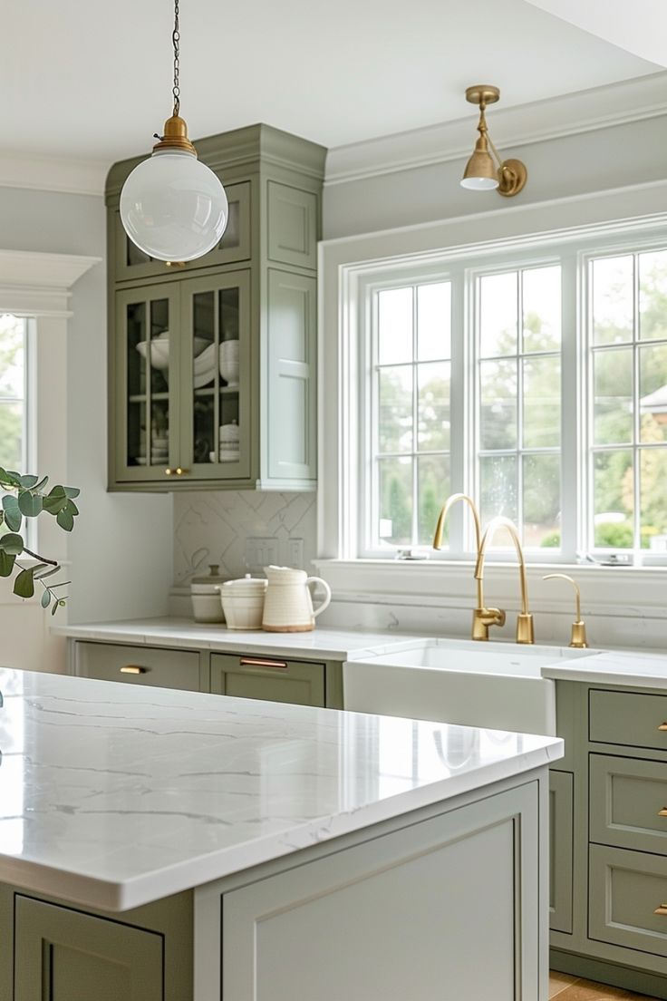 a kitchen with green cabinets and marble counter tops, along with an island in the middle