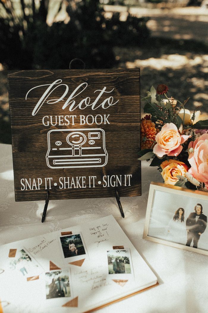 a wooden sign sitting on top of a table next to pictures and flowers in vases