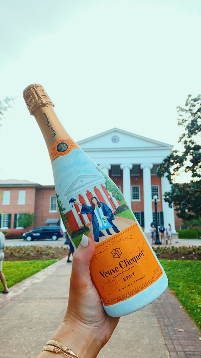 a person holding up a bottle of champagne in front of a building with people on it