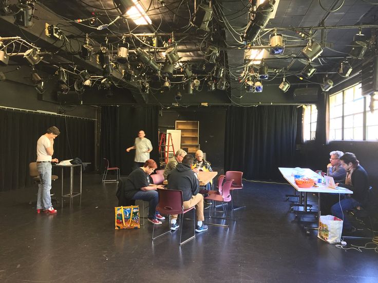 people are sitting at tables in an empty room with black drapes on the ceiling