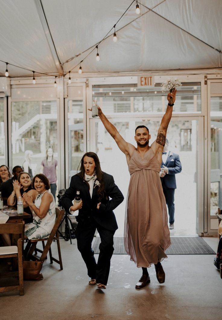 a man and woman are walking down the aisle with their arms in the air