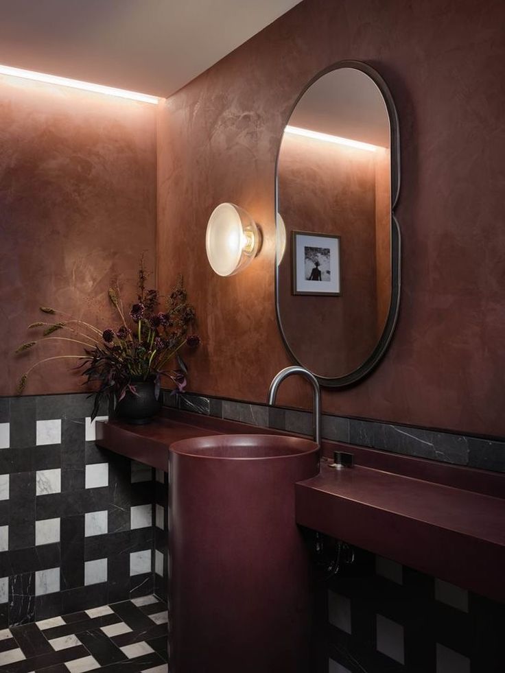 a bathroom with a sink, mirror and tiled flooring in brown tones on the walls