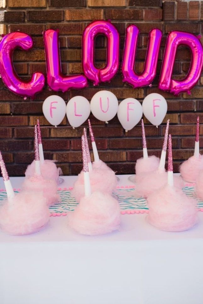 pink cotton balls and candles on a table with balloons in the shape of unicorns