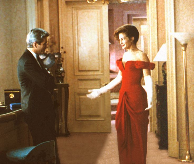 a woman in a red dress standing next to a man