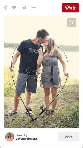 a man and woman standing next to each other in front of a body of water