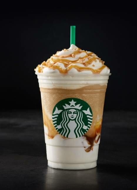 a starbucks drink with caramel and whipped cream on it's top, sitting on a black surface