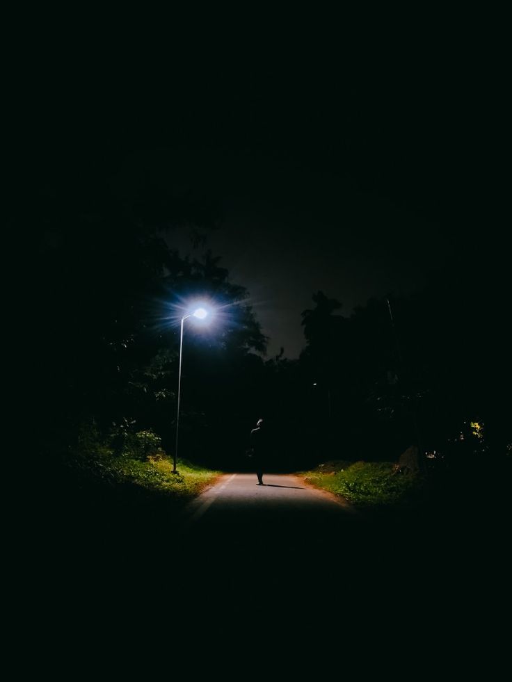 A person walking alone at night is captured near a street lamp. Alone At Night, Boy Walking, Night Video, Happy Returns, Sprained Ankle, Walking Alone, Road Running, Cinematography, At Night