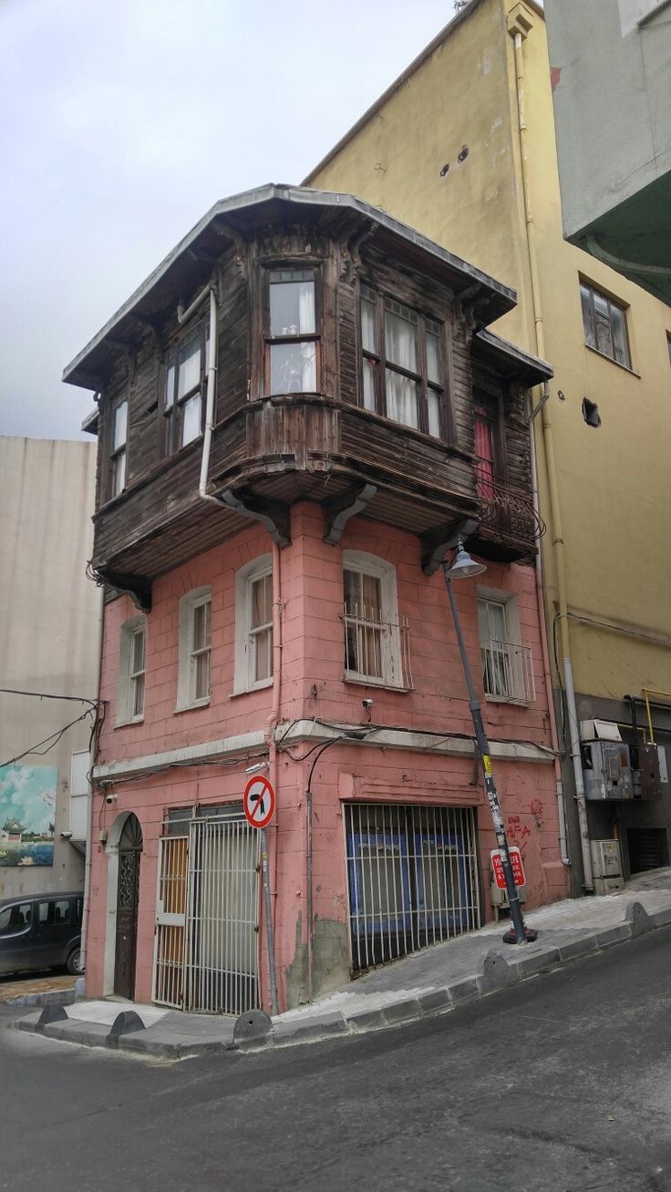 an old pink building on the corner of a street in front of two tall buildings