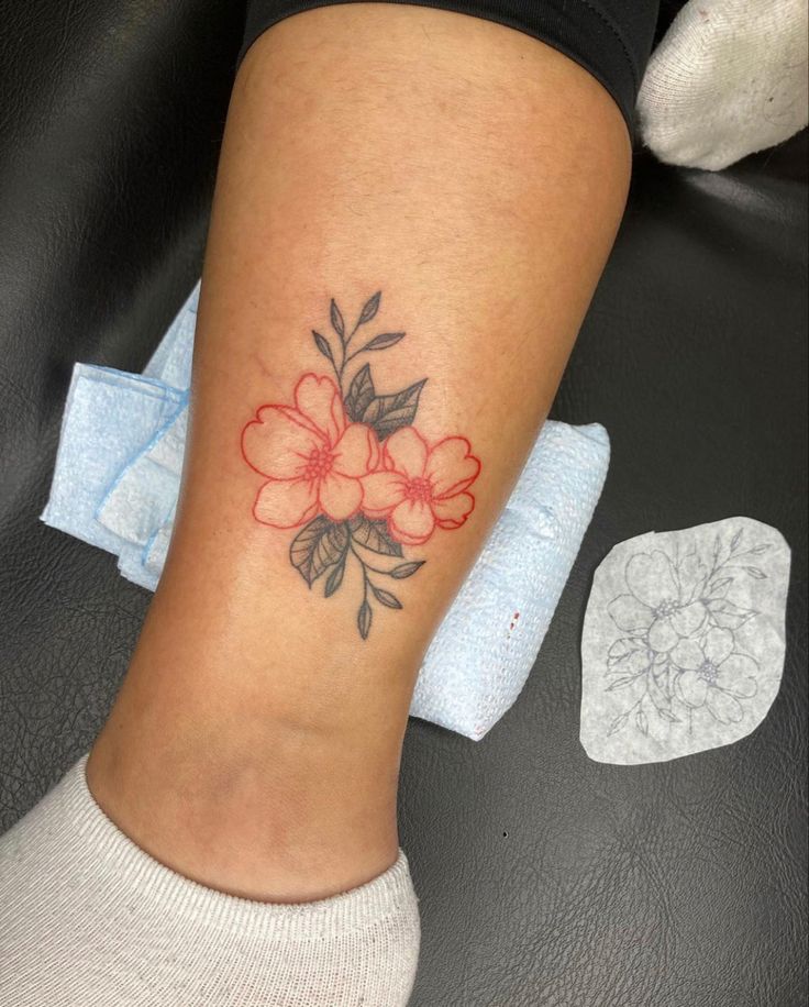 a woman's foot with a flower tattoo on her left leg and the word love written in red ink