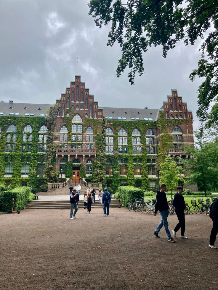 people walking in front of a building with ivy growing on it