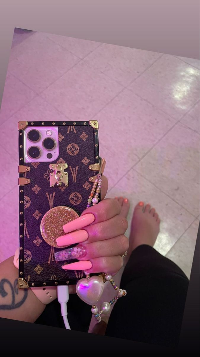 a woman with pink nail polish holding up her phone case