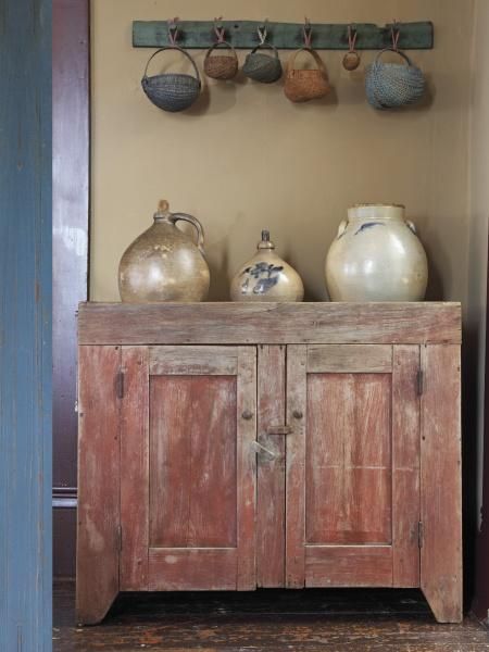 an old wooden cabinet with pots and vases on top