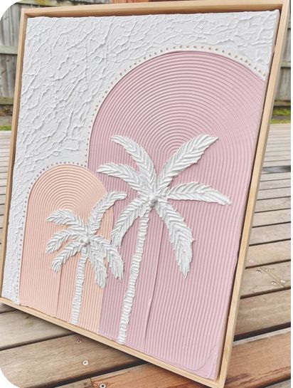 a pink and white card with palm trees in the background on a wooden bench outside