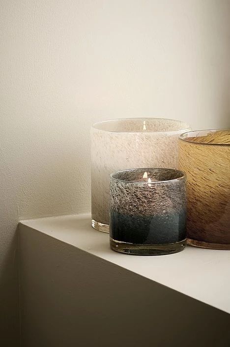 two candles sitting on top of a white shelf