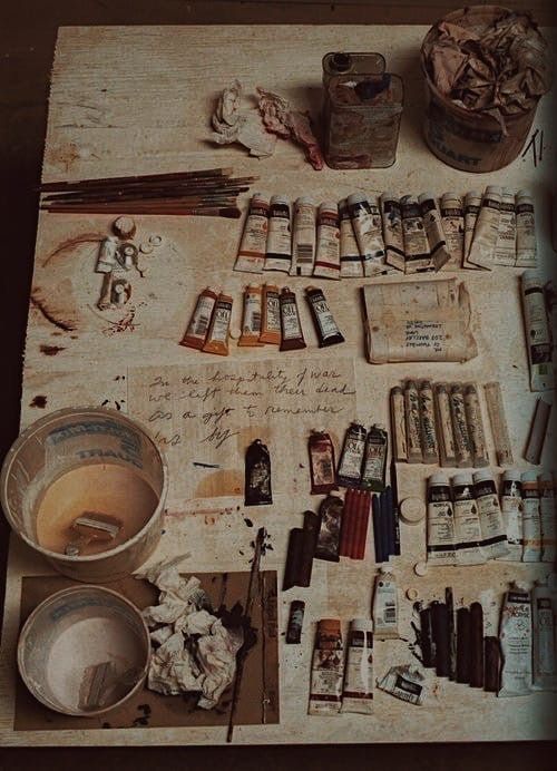 an artist's workbench with paint, brushes and other items on it