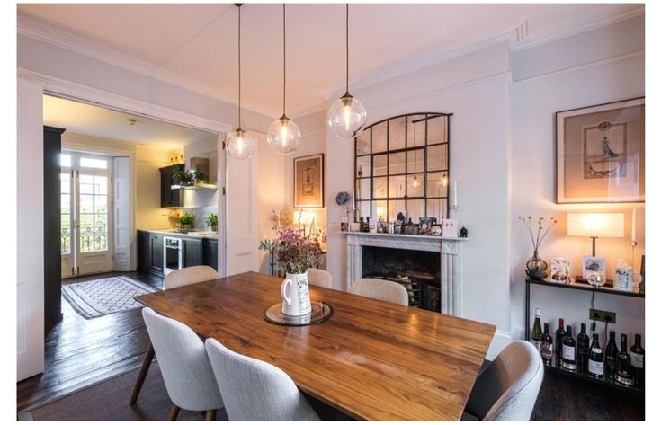 a dining room table with white chairs and a fireplace in the backround behind it