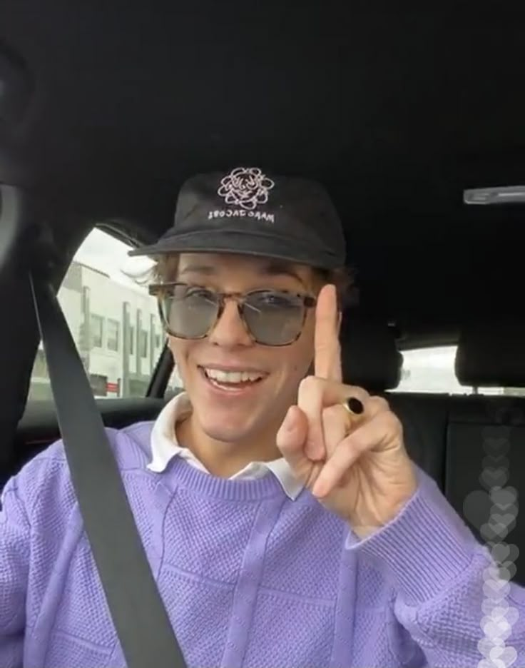 a man sitting in the back seat of a car holding up a peace sign