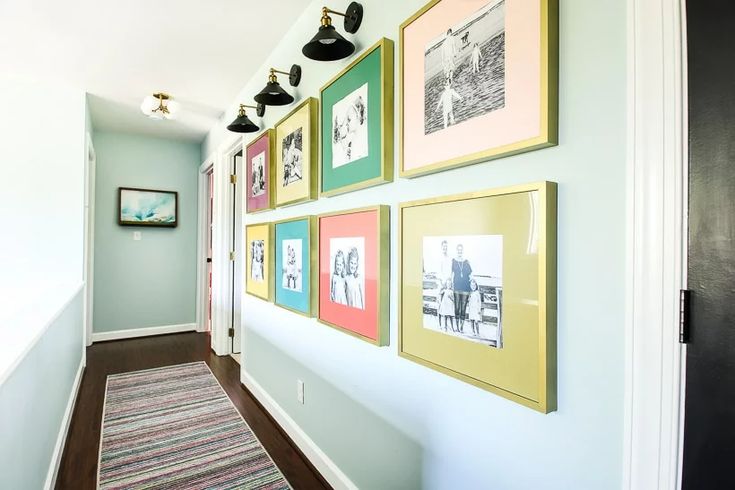 a hallway with pictures on the wall and carpeted flooring in front of it