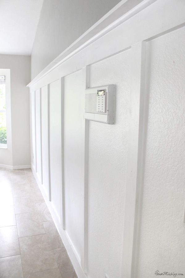 a hallway with white walls and an electrical device mounted to the side of the wall