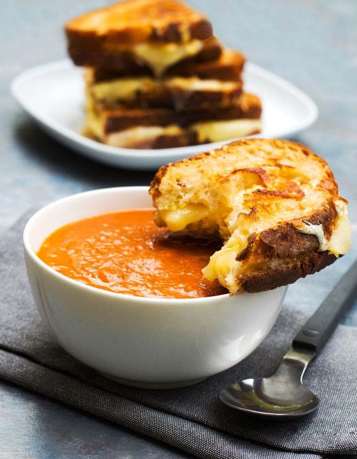 a bowl of tomato soup with grilled cheese on top