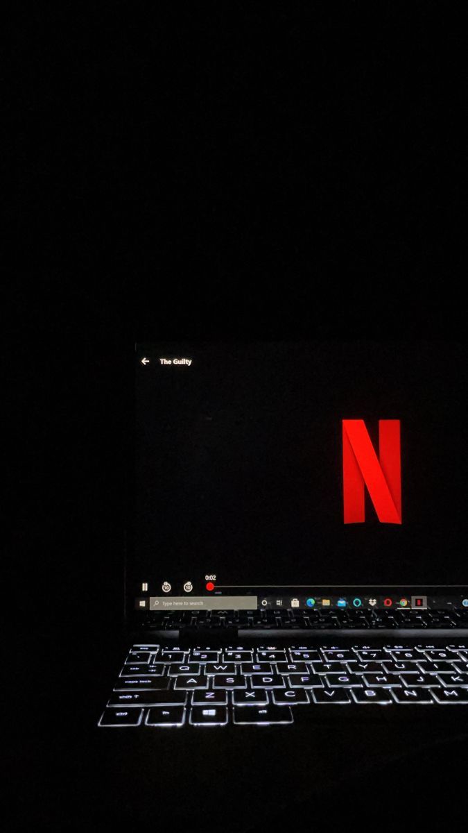 an open laptop computer sitting on top of a black table in the dark with red letters