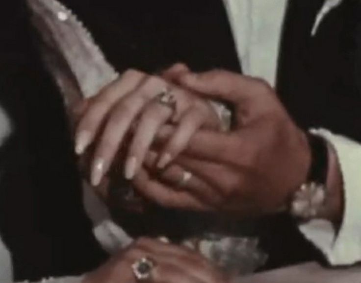 a man and woman holding each other's hands while sitting down together at a table