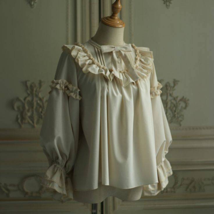 For a beautiful and elegant young lady. The blouse is richly decorated with frills and lace embroidery around her shoulders. Her sleeves have a relatively loose silhouette, and her chest is decorated with a ribbon. Her graceful beauty overflows. Bring romance to your everyday life. 
 
 

 

 
 
 Size 
 
 S size 
 
 Neck circumference: 40cm or less 
 Shoulder width: 38cm or less 
 Bust: 98cm or less 
 
 M size 
 
 Neck circumference: 45cm or less 
 Shoulder width: 42cm or less 
 Bust: 118cm or le Elegant Blouse With Ruffled Collar And Ruffle Hem, Elegant Blouse With Ruffles And Ruffled Collar, Feminine Blouse With Ruffled Collar For Formal Occasions, Elegant Beige Tops With Lace Collar, Feminine Collared Blouse With Ruffles, Feminine White Blouse With Ruffles, Party Blouse With Ruffles And Collar, Cream Ruffled Top For Party, Feminine Formal Blouse With Ruffles