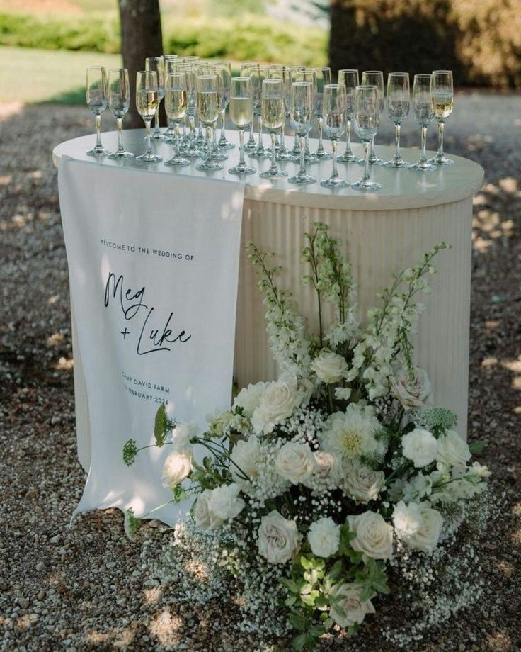 there are many wine glasses on the table and flowers in the vases next to it