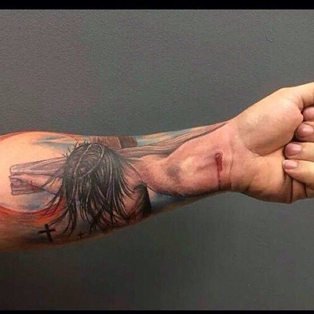 a man's arm with a cross on it and a person holding his hand