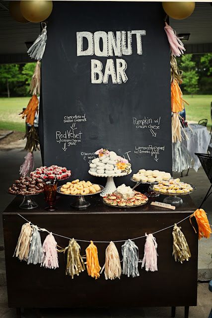 a table topped with lots of desserts next to a chalkboard sign that says donut bar