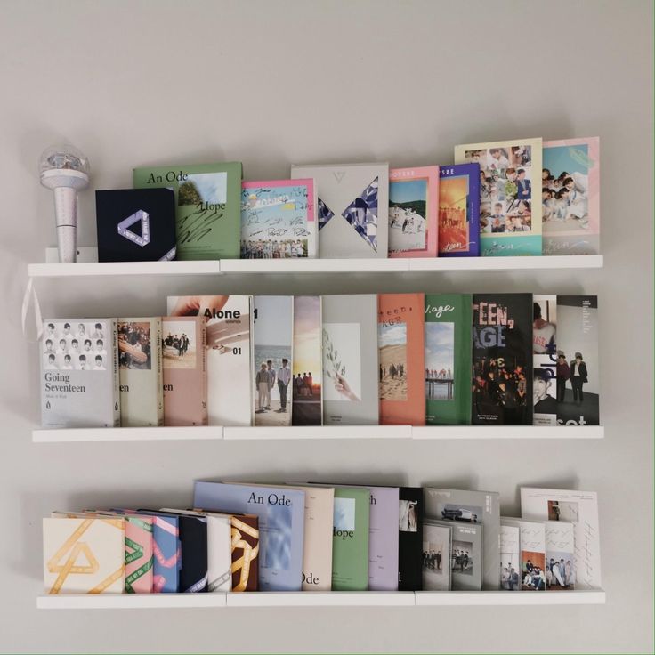 two white shelves filled with books on top of each other next to a wall mounted speaker