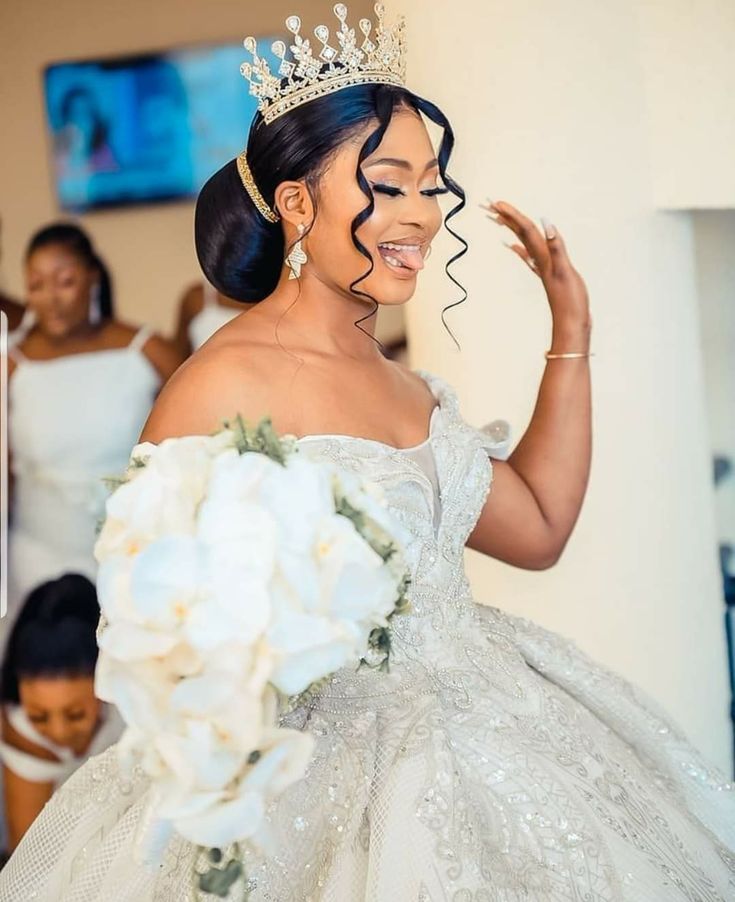 a woman wearing a tiara and holding a bouquet in front of her face with other women behind her