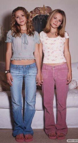 two young women standing next to each other in front of a white couch and chair