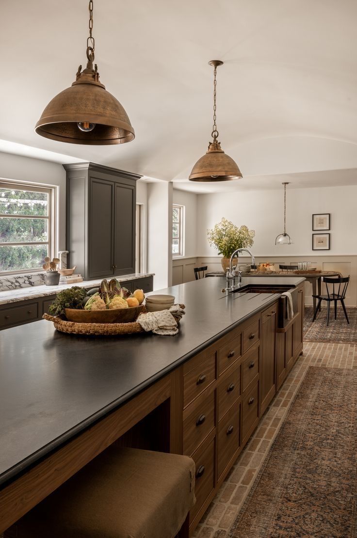 a large kitchen with lots of counter space and hanging lights over the top of it