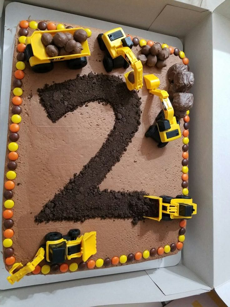 a birthday cake decorated with construction vehicles and chocolate frosting in the shape of number two