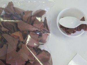 there is a bowl and spoon on the table next to some chocolate pieces in plastic bags