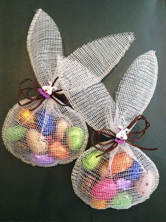 three mesh bags filled with colorful eggs on top of a black tablecloth covered surface