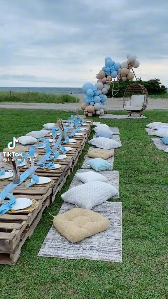 a long table set up with blue balloons and plates on top of wooden pallets