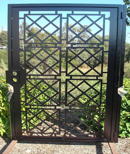 an iron gate in the middle of some bushes