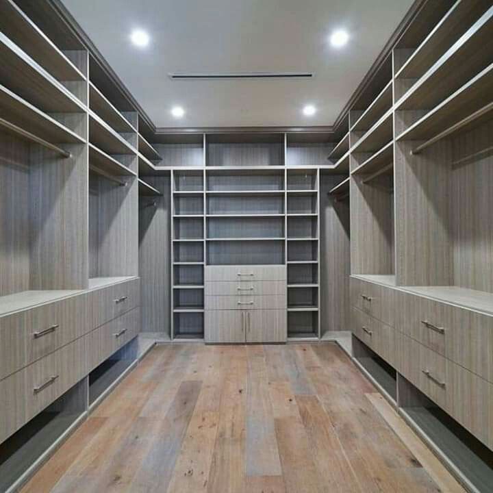 an empty walk - in closet with wooden flooring and built - in shelving