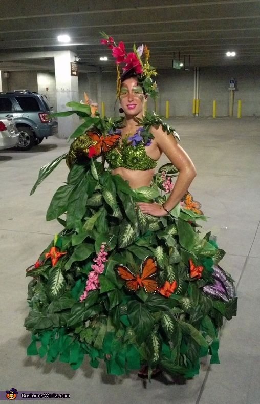 a woman in a green dress with butterflies on her head and leaves around her body