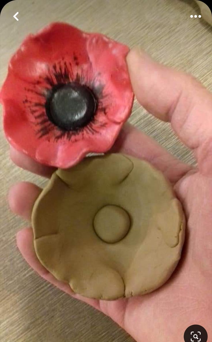 a person holding two clay flowers in their hand