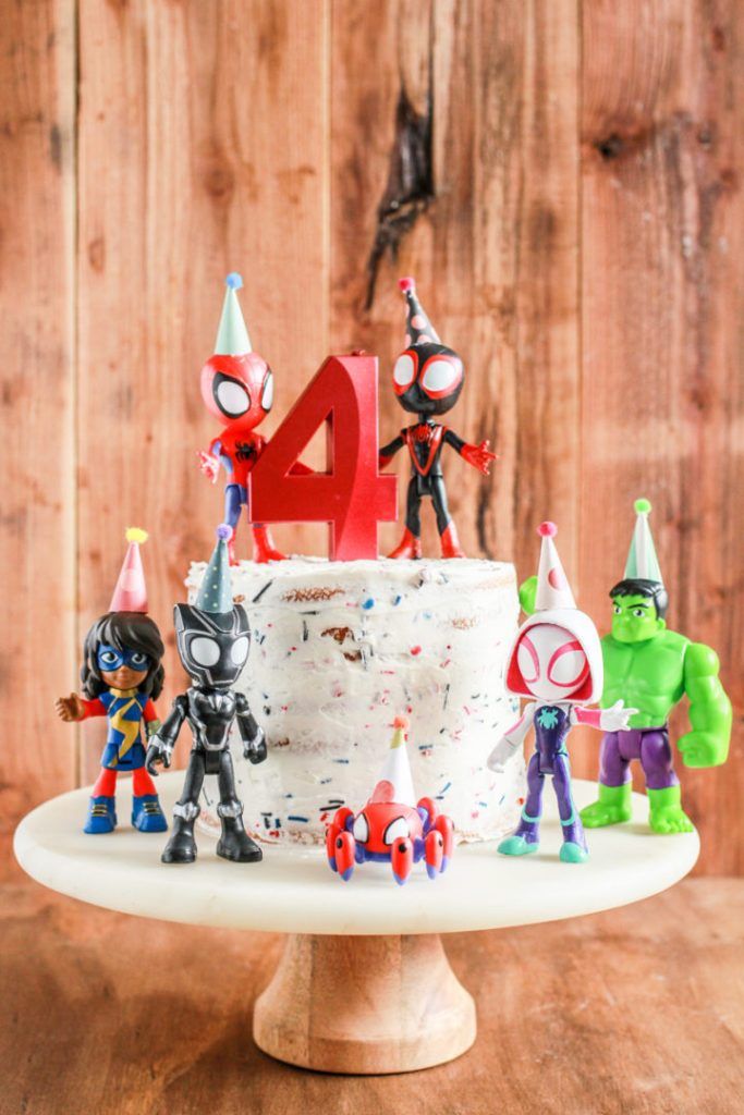 a birthday cake with toy figurines on it and the number four spelled out