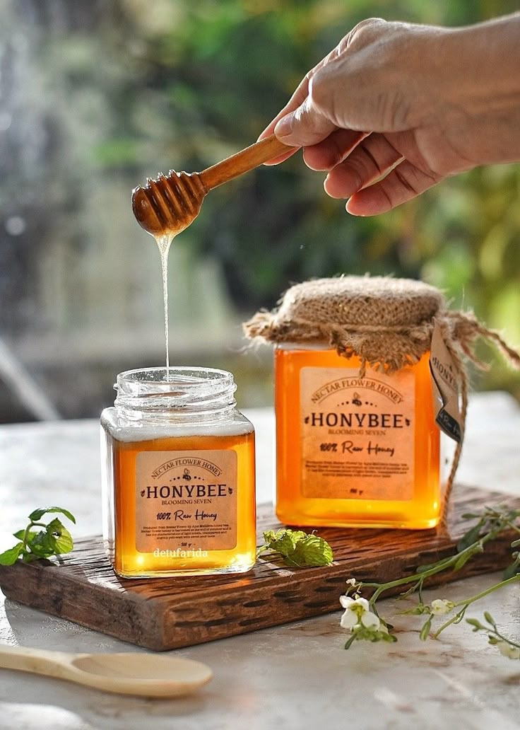 a person is pouring honey into jars on a table