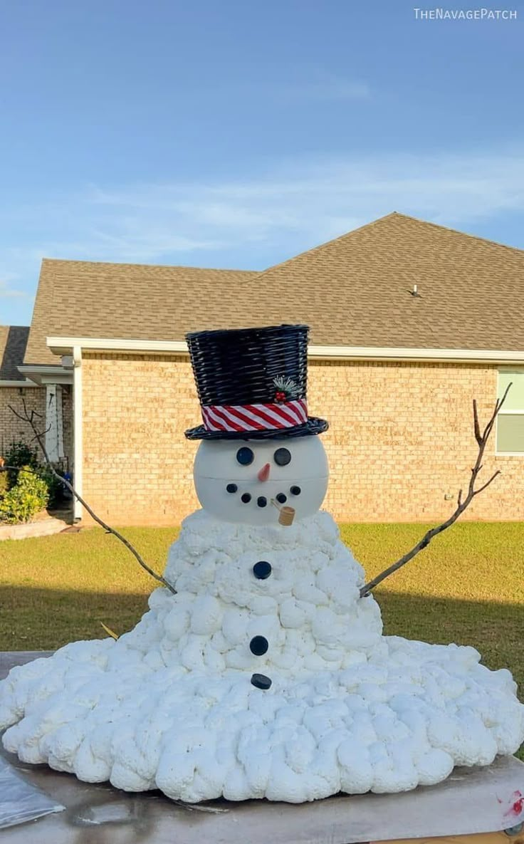 a snowman made out of cotton balls in front of a house