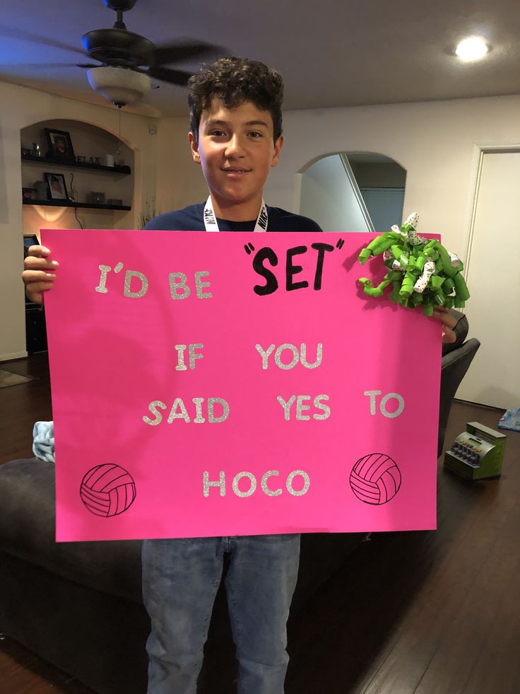 a man holding up a pink sign that says i'd be set if you said yes to hoco