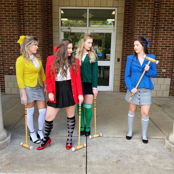 four young women dressed in school uniforms holding crutches and standing on the sidewalk