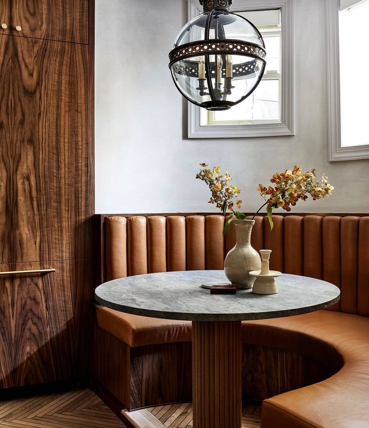 a vase with flowers sitting on top of a table next to a bench in a room