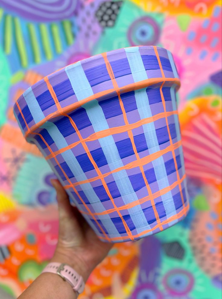 a hand holding up a paper cup in front of a colorful wall